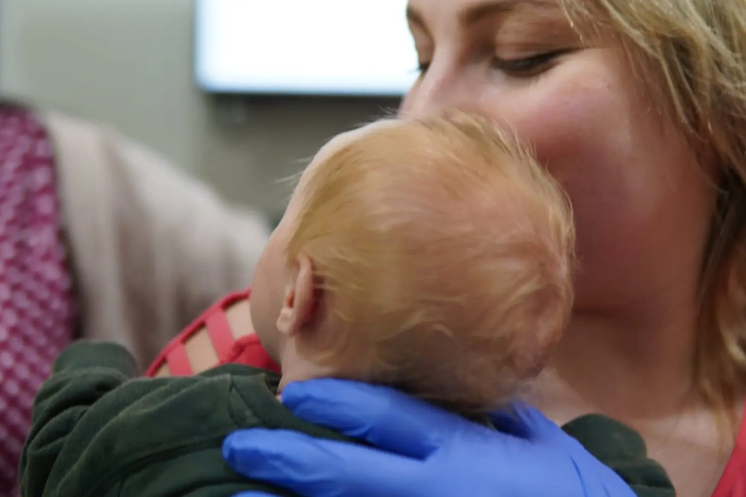 Gloved hand gently supporting a baby head during cranial work at the Sea Girt NJ office