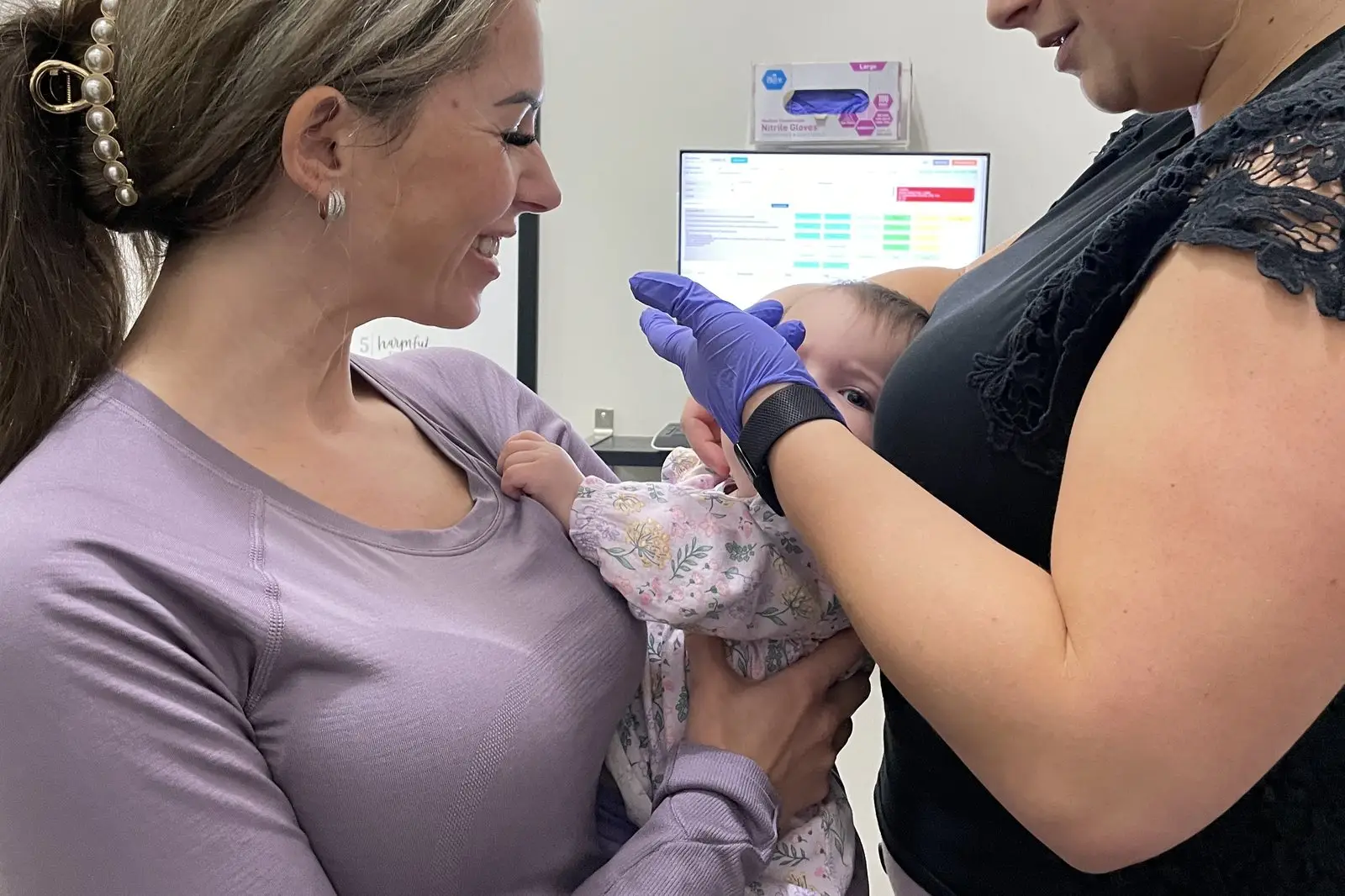 Chiropractor assessing a baby head and neck while a parent holds the baby