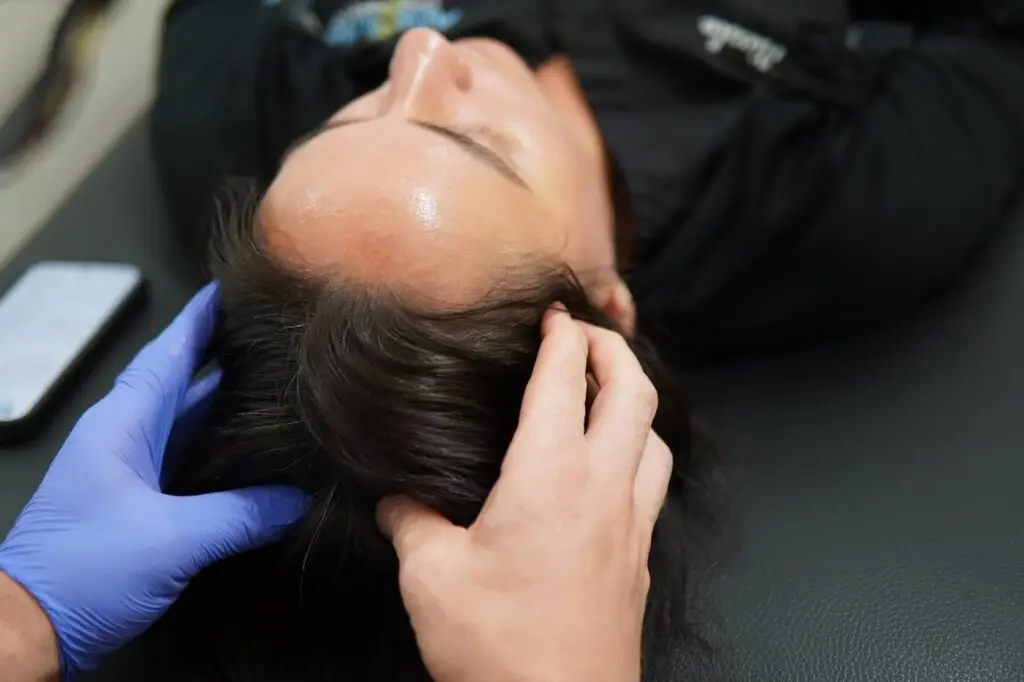 A chiropractor checking motion and tension at the top of the neck during a jaw evaluation